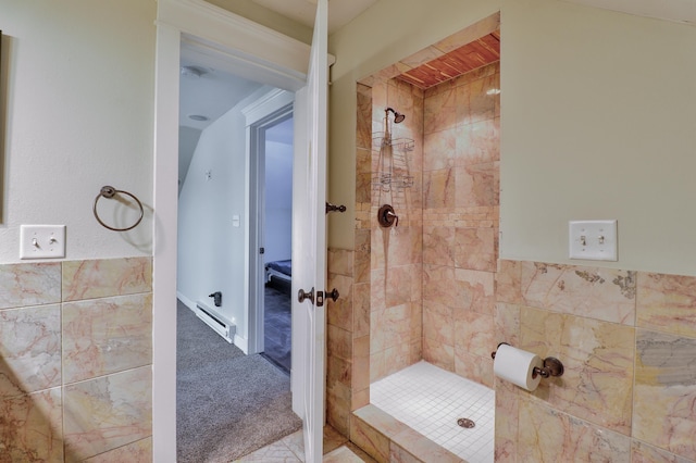 bathroom with tiled shower, baseboard heating, and tile walls