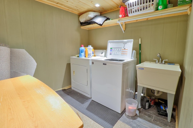 laundry room featuring wood-type flooring, washing machine and dryer, wooden ceiling, and sink