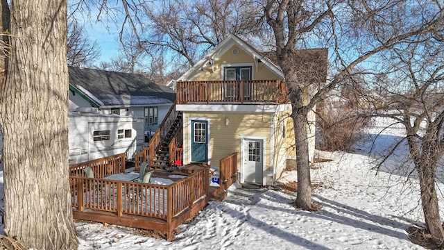 snow covered back of property featuring a balcony