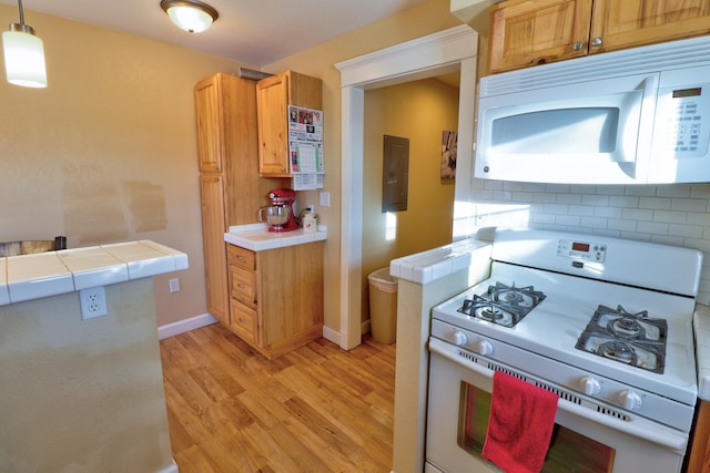 kitchen featuring decorative backsplash, light wood-type flooring, white appliances, pendant lighting, and tile countertops