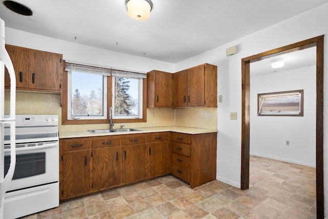 kitchen with decorative backsplash, white stove, and sink