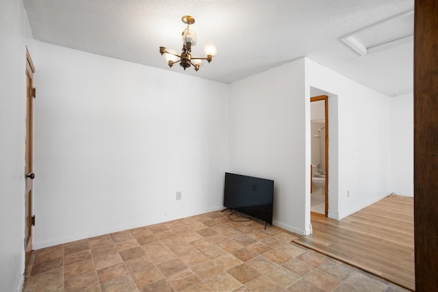 empty room featuring light hardwood / wood-style floors, a textured ceiling, and a notable chandelier