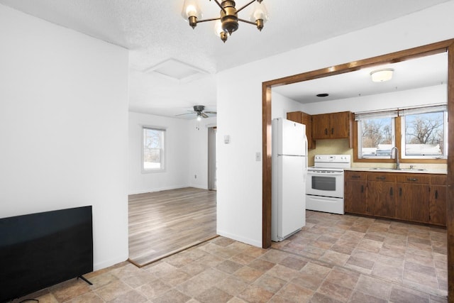 kitchen featuring sink, a notable chandelier, light hardwood / wood-style floors, a textured ceiling, and white appliances