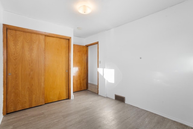 unfurnished bedroom with hardwood / wood-style floors and a closet