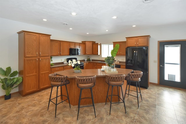 kitchen featuring black appliances, a breakfast bar, and a center island