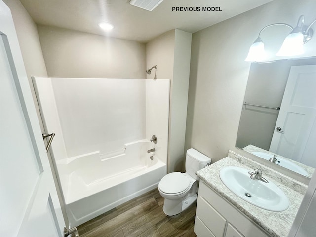 full bathroom with washtub / shower combination, vanity, hardwood / wood-style flooring, and toilet