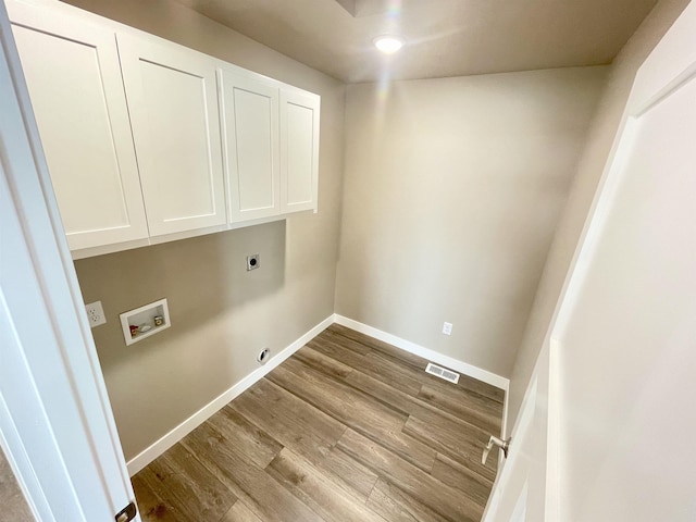 washroom with washer hookup, electric dryer hookup, cabinets, and light wood-type flooring