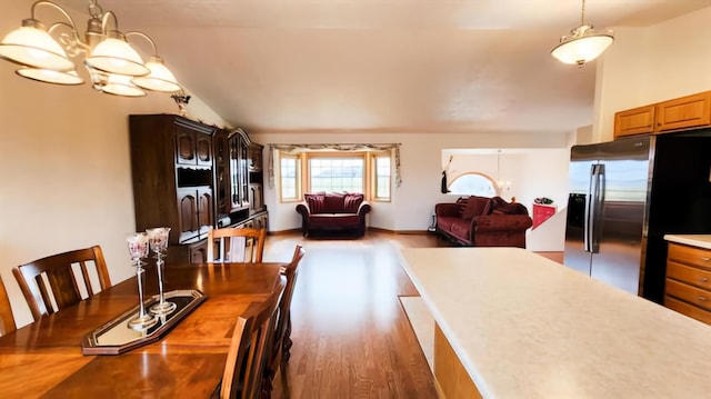 dining area featuring hardwood / wood-style flooring, lofted ceiling, and an inviting chandelier