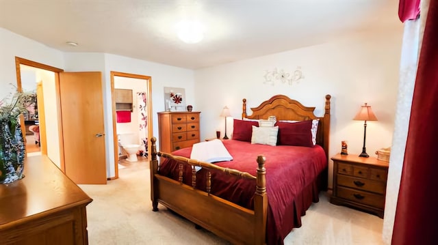 bedroom with ensuite bathroom and light colored carpet