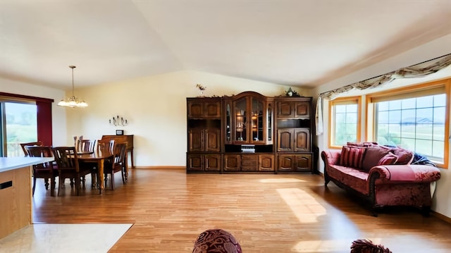 living room featuring light hardwood / wood-style flooring, lofted ceiling, and a notable chandelier