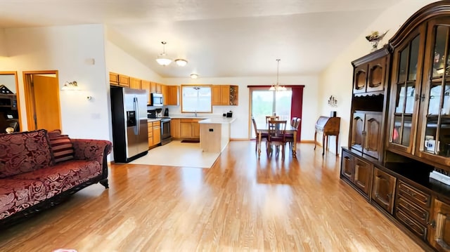 interior space with a center island, stainless steel appliances, pendant lighting, lofted ceiling, and light hardwood / wood-style floors