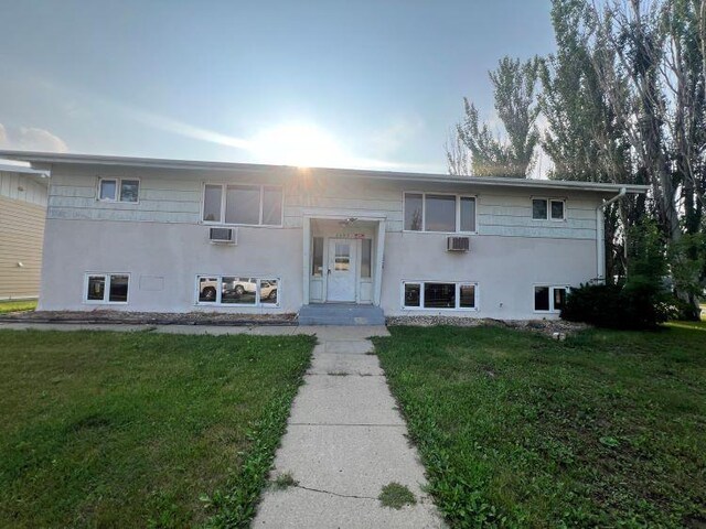 view of front facade with a wall mounted AC and a front yard