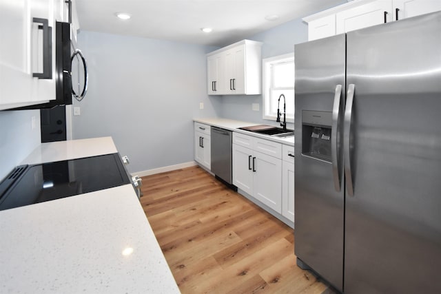 kitchen with white cabinets, light hardwood / wood-style floors, sink, and appliances with stainless steel finishes