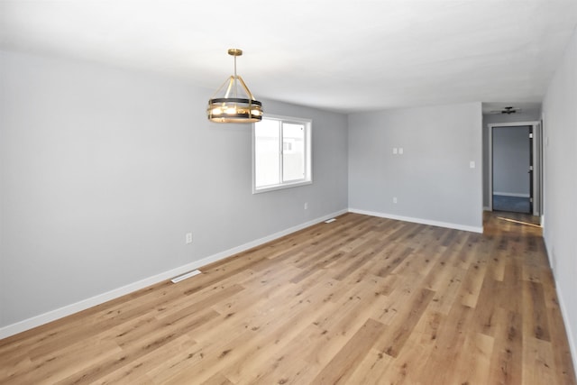 empty room featuring a chandelier and wood-type flooring