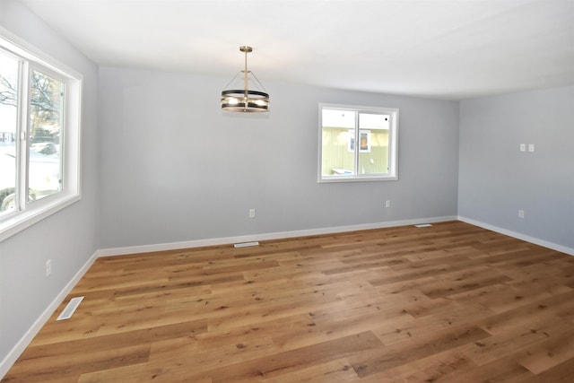 unfurnished room featuring a chandelier and wood-type flooring