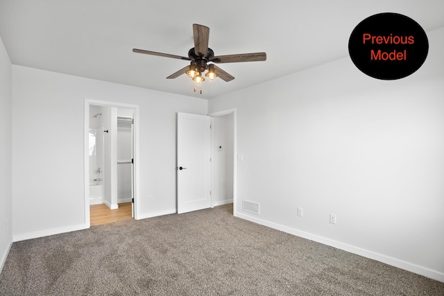 unfurnished bedroom featuring ensuite bath, ceiling fan, light colored carpet, and a spacious closet