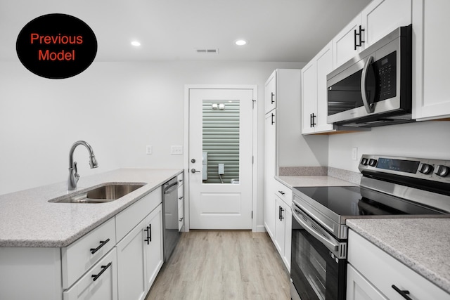 kitchen featuring white cabinets, light wood-type flooring, stainless steel appliances, and sink