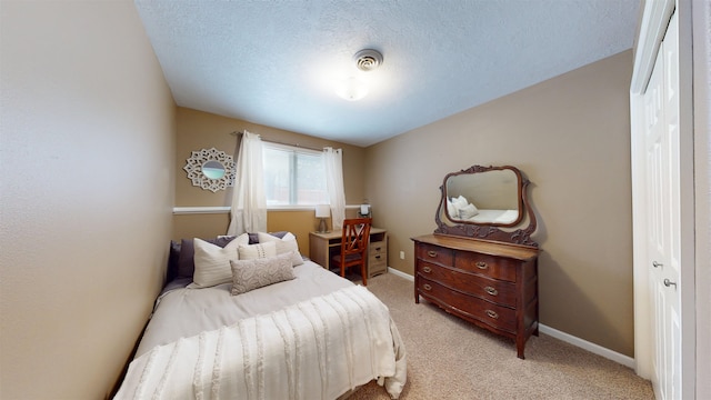 bedroom with light carpet, a textured ceiling, and a closet