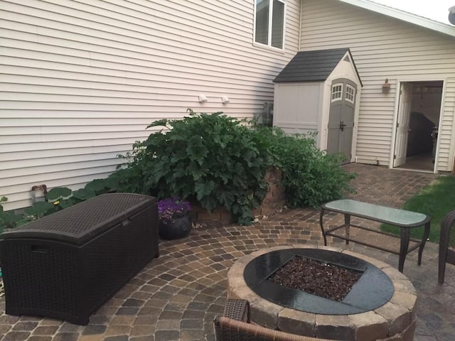 view of patio with a shed and an outdoor fire pit