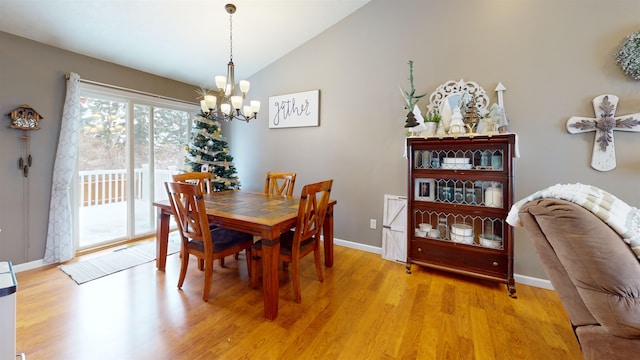 dining room with light hardwood / wood-style flooring, vaulted ceiling, and an inviting chandelier