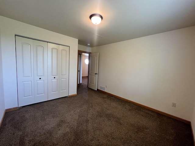 unfurnished bedroom with a closet and dark colored carpet