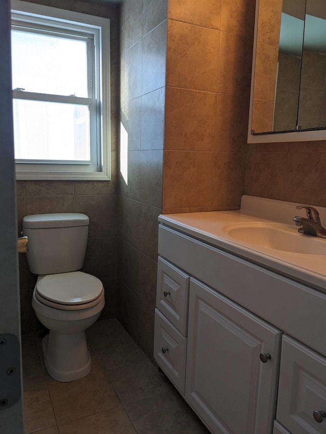 bathroom featuring tile patterned floors, vanity, toilet, and tile walls