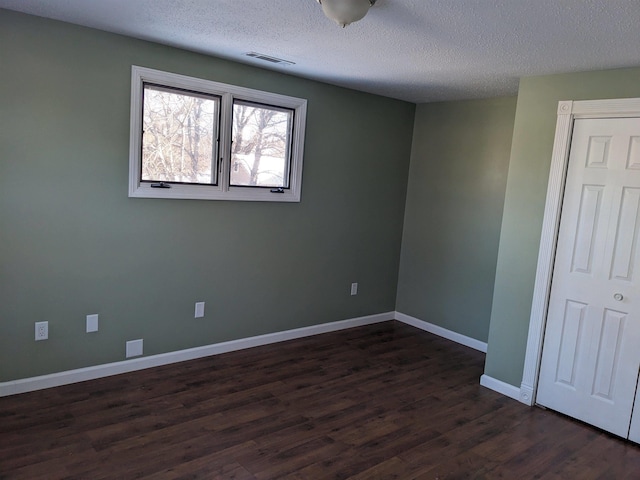 spare room featuring a textured ceiling and dark wood-type flooring