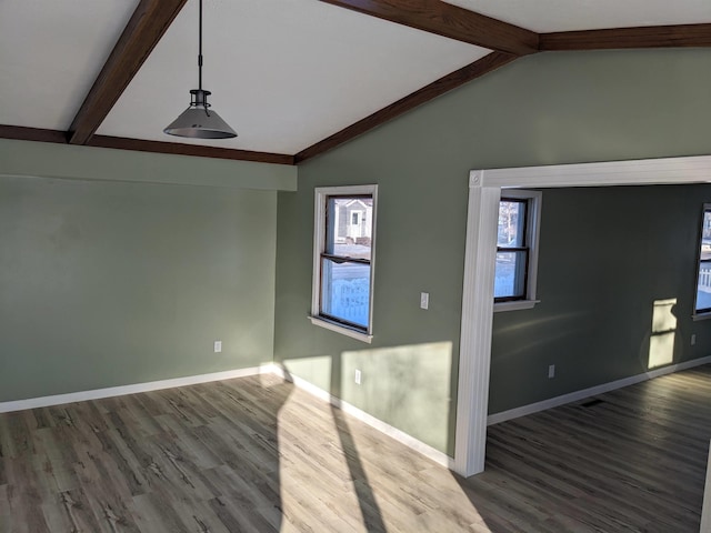 spare room featuring vaulted ceiling with beams and hardwood / wood-style flooring