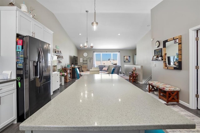 kitchen with white cabinetry, light stone counters, pendant lighting, lofted ceiling, and black fridge with ice dispenser