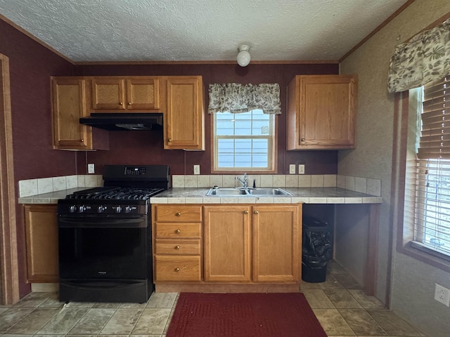 kitchen with gas stove, tile countertops, sink, and a textured ceiling