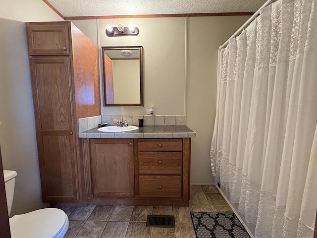 bathroom featuring vanity, a textured ceiling, toilet, and curtained shower