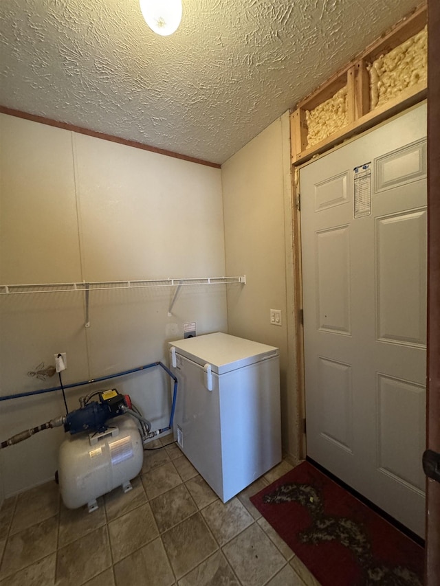 laundry room featuring crown molding, tile patterned flooring, and a textured ceiling