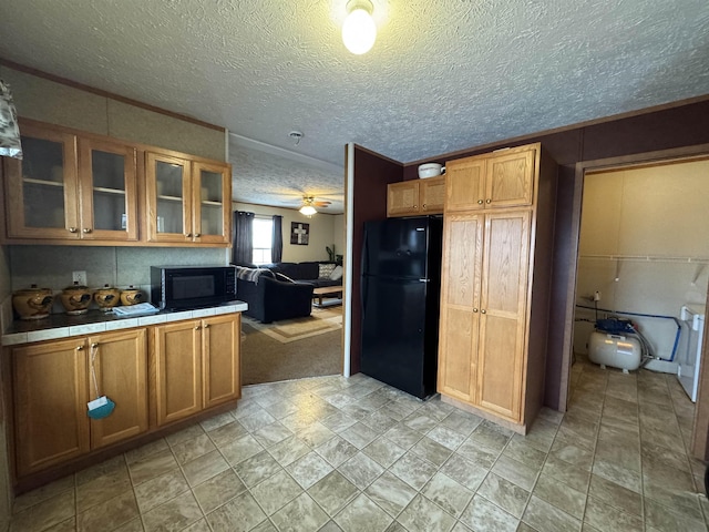 kitchen with ceiling fan, a textured ceiling, tile counters, and black appliances