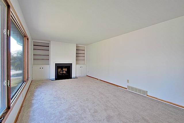 unfurnished living room featuring carpet flooring and built in features