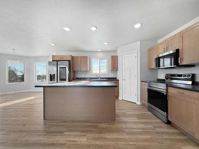 kitchen with sink, light hardwood / wood-style flooring, decorative light fixtures, a kitchen island, and stainless steel appliances