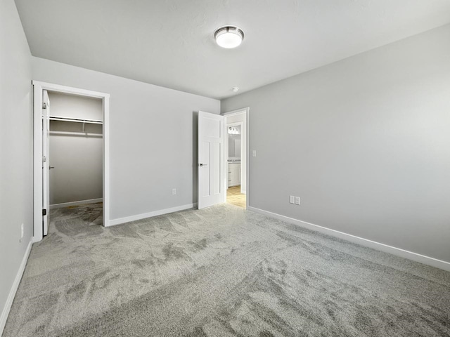 unfurnished bedroom featuring a walk in closet, light carpet, and a closet