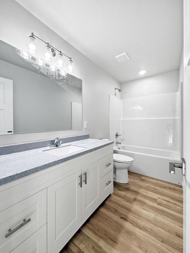 full bathroom featuring hardwood / wood-style floors, vanity, shower / bathtub combination, and toilet