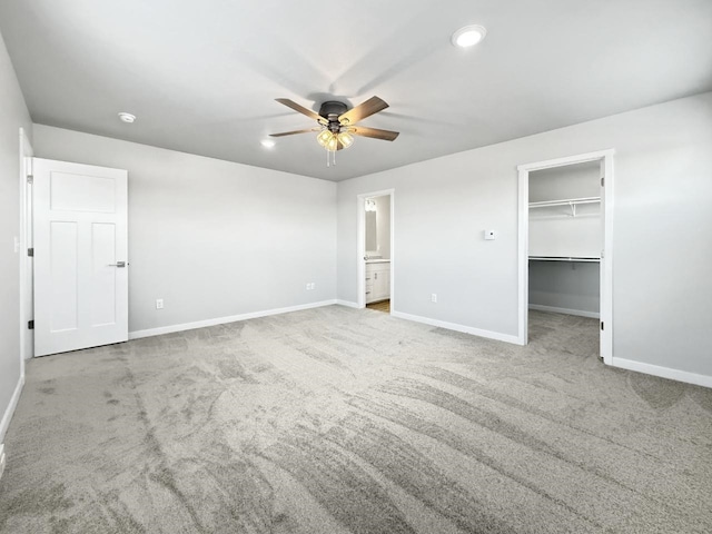 unfurnished bedroom with ensuite bath, ceiling fan, a spacious closet, light colored carpet, and a closet