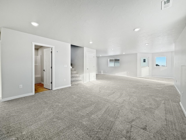 unfurnished living room with carpet floors and a textured ceiling