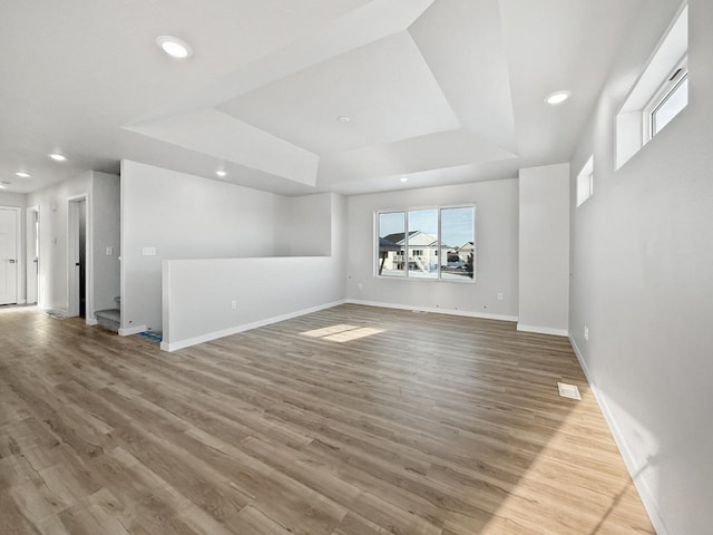 unfurnished living room with light hardwood / wood-style floors and a raised ceiling