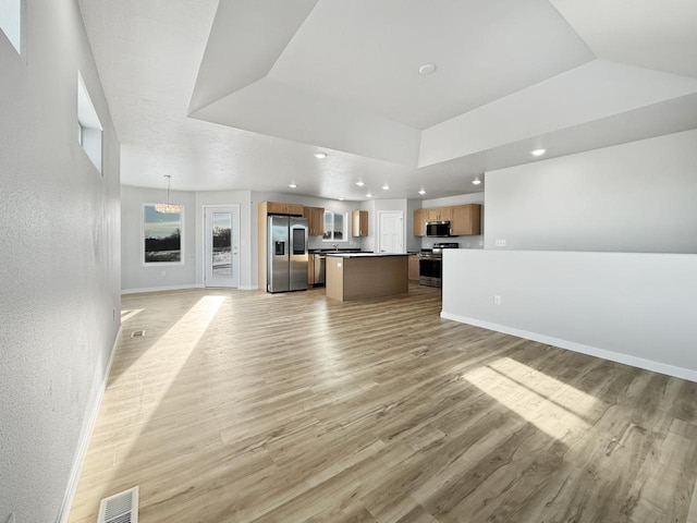 unfurnished living room with light hardwood / wood-style floors and a tray ceiling