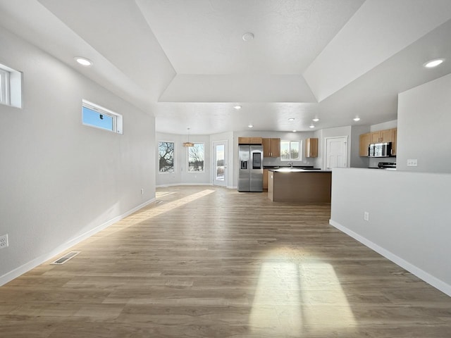 unfurnished living room featuring vaulted ceiling, sink, and light hardwood / wood-style flooring