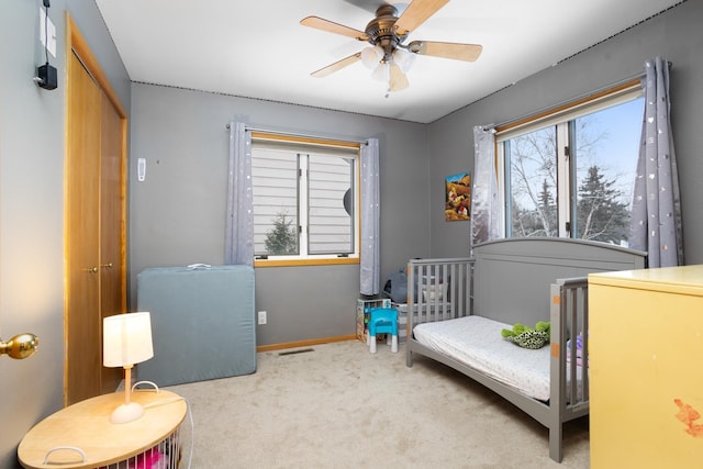 carpeted bedroom featuring multiple windows, ceiling fan, and a closet