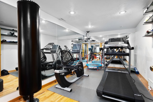 exercise room featuring light hardwood / wood-style floors and a textured ceiling