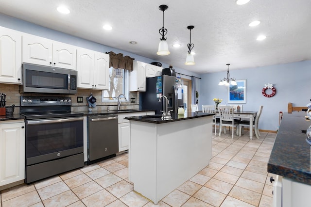 kitchen featuring sink, stainless steel appliances, hanging light fixtures, and an island with sink