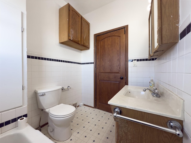 bathroom featuring vanity, a bathtub, toilet, and tile walls