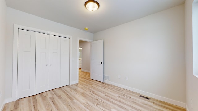 unfurnished bedroom with light hardwood / wood-style flooring and a closet