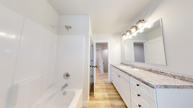 bathroom with hardwood / wood-style flooring, vanity, and tub / shower combination