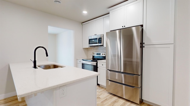 kitchen featuring stainless steel appliances, sink, a center island with sink, light hardwood / wood-style flooring, and white cabinetry