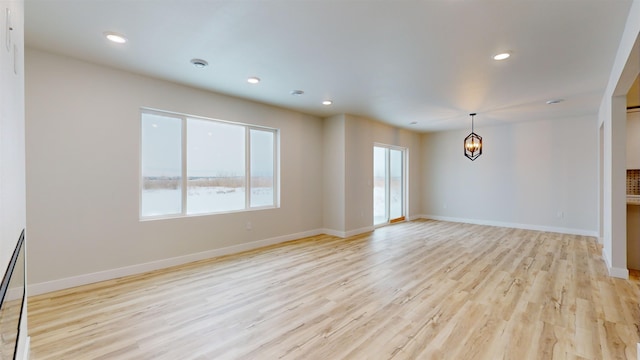 unfurnished living room featuring light hardwood / wood-style flooring and a notable chandelier